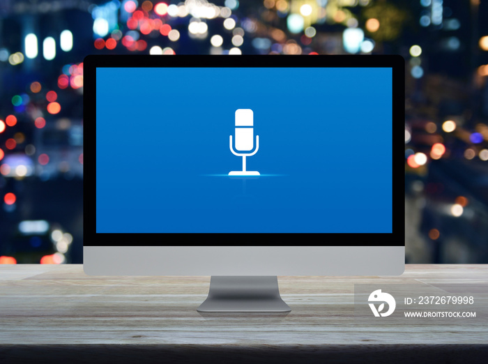 Microphone flat icon on desktop modern computer monitor screen on wooden table over blur colorful ni