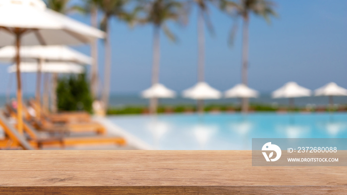 Empty wood table top and blurred swimming pool in tropical resort in summer banner background - can 