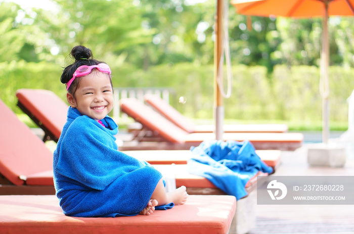 亚洲儿童或女孩微笑着戴上护目镜，坐在床上或台球椅上，身上裹着毯子毛巾