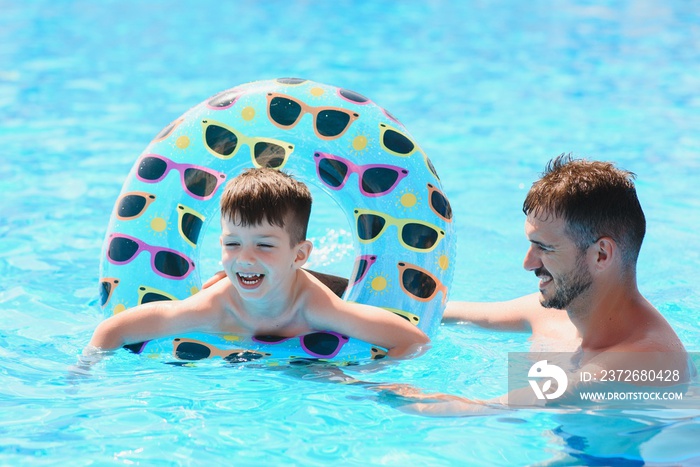 父亲和儿子在游泳池玩得很开心。家庭度假