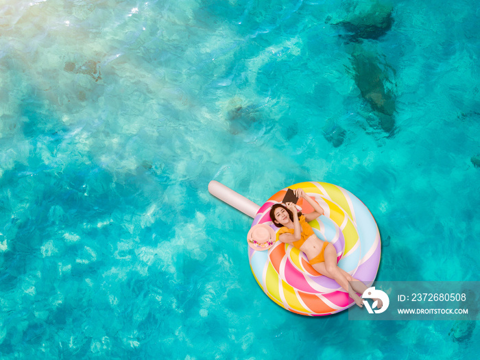 woman bikini enjoy with mobile tablet playing, laying in inflamable tube in the sea water, enjoy fee