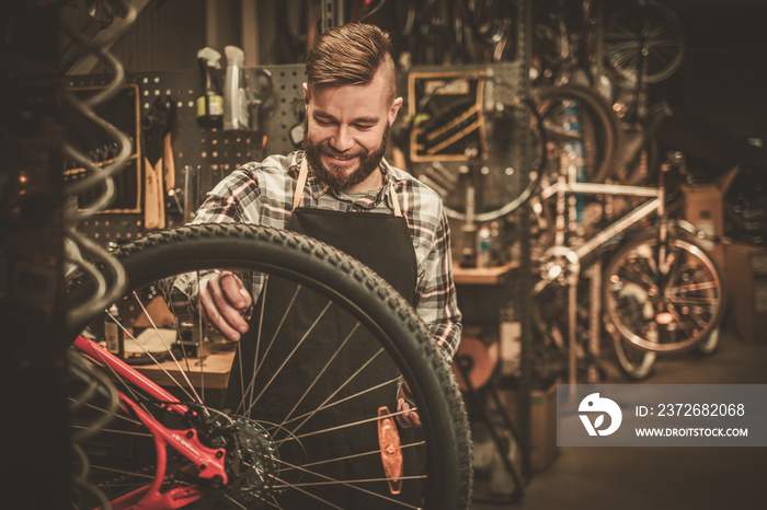Stylish bicycle mechanic doing his professional work in workshop