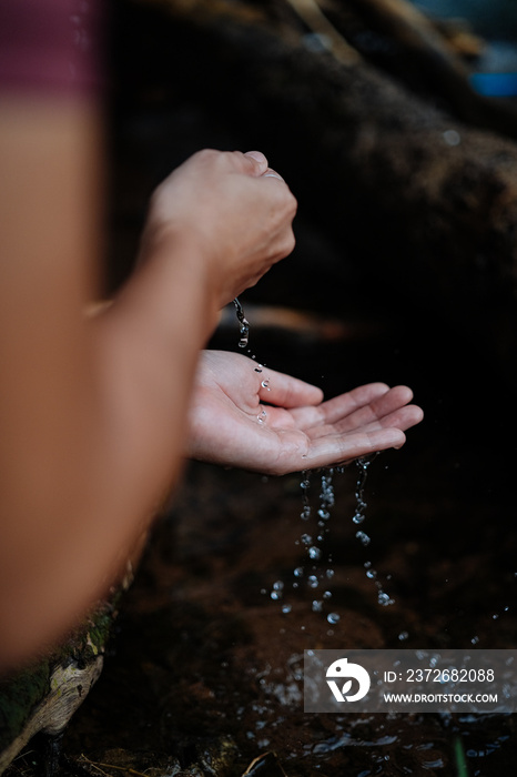 A young female cyclist is washing her hands by the creek