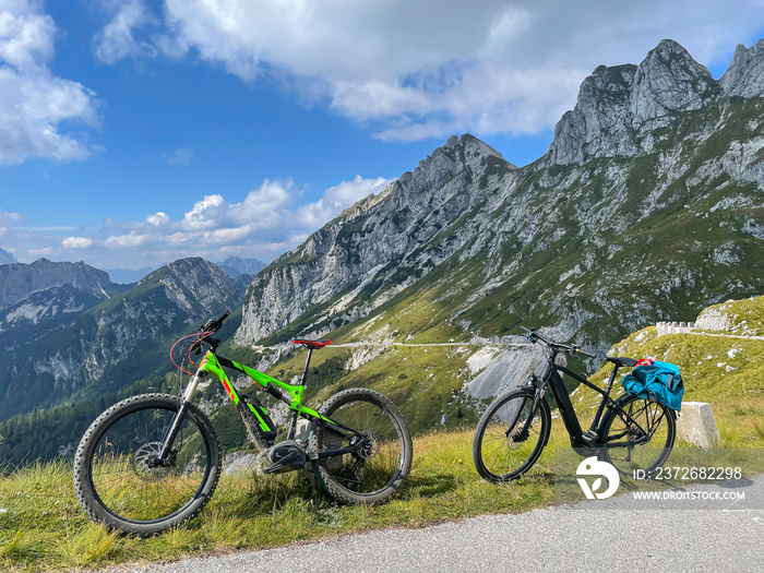 Two electric bicycles are parked next to an scenic mountain road in Slovenia.