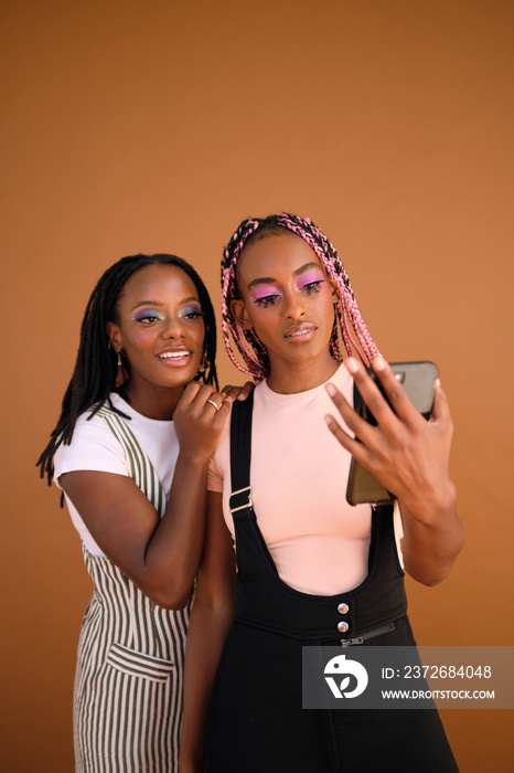 Studio portrait of young beautiful queer couple smiling with phone