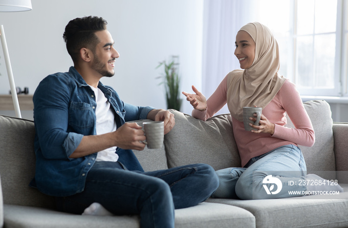 Young muslim couple drinking coffee and having conversation at home