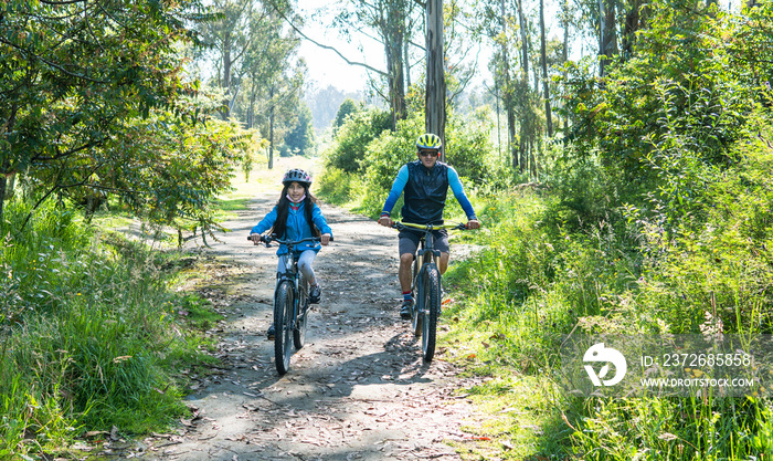 一对父女在森林里的乡间小路上骑山地自行车