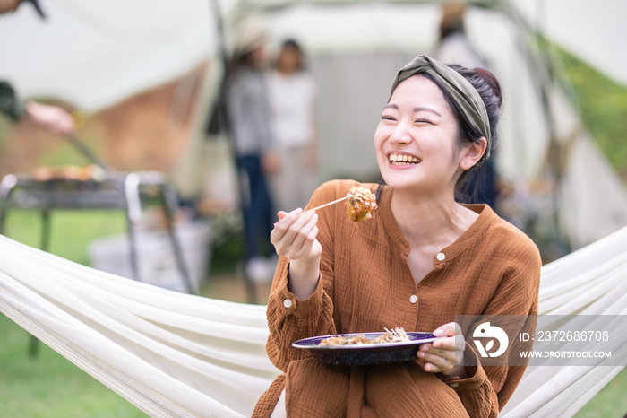 キャンプでたこ焼きを食べる女性