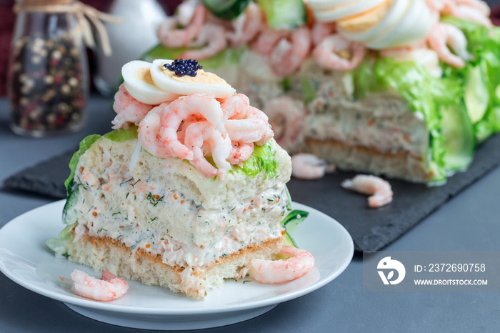 Piece of traditional savory swedish sandwich cake Smorgastorta with bread, shrimps, eggs, caviar, di