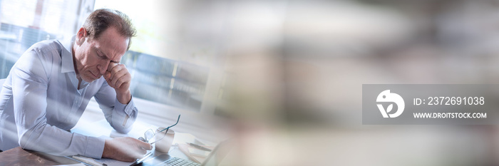 Tired businessman sitting in office, light rays effect; panoramic banner