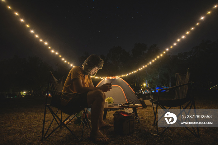 亚洲男人独自露营十次，坐在夜空下的椅子上。在森林里露营帐篷，Lo