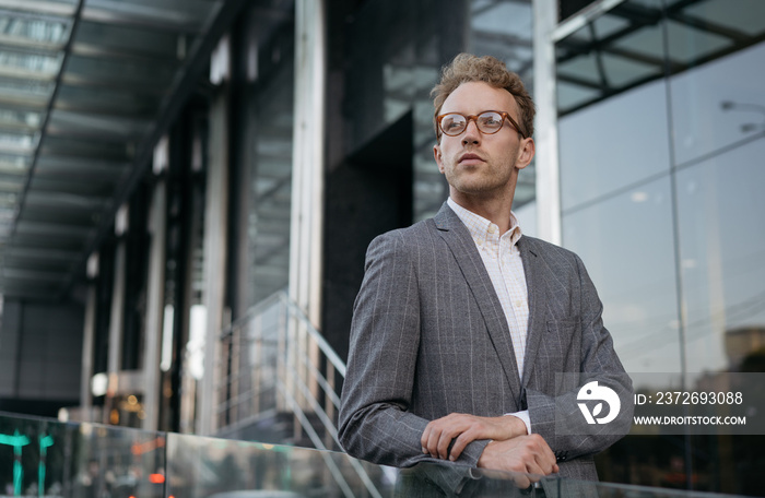 Pensive manager wearing suit, stylish eyeglasses planning project looking away at copy space. Portra