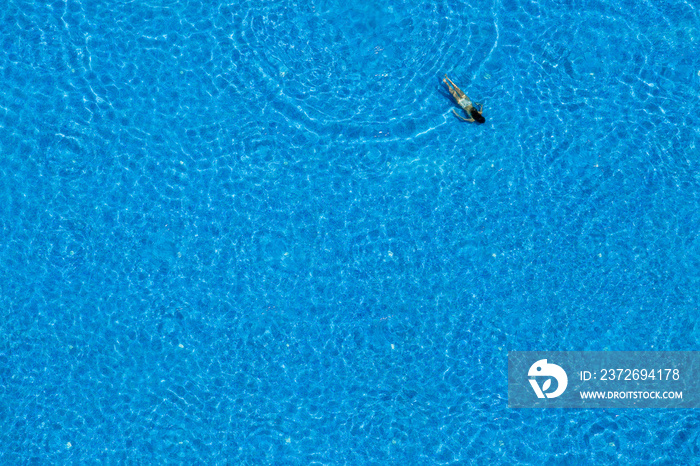 Young girl swims in the swimming pool, view from above