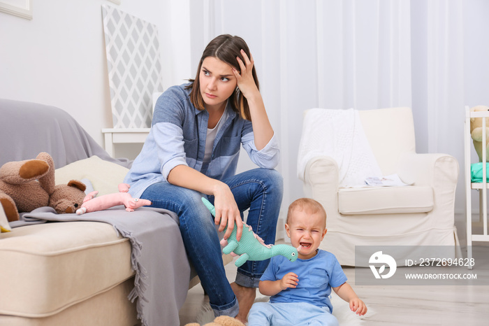 Depressed young woman with cute baby at home