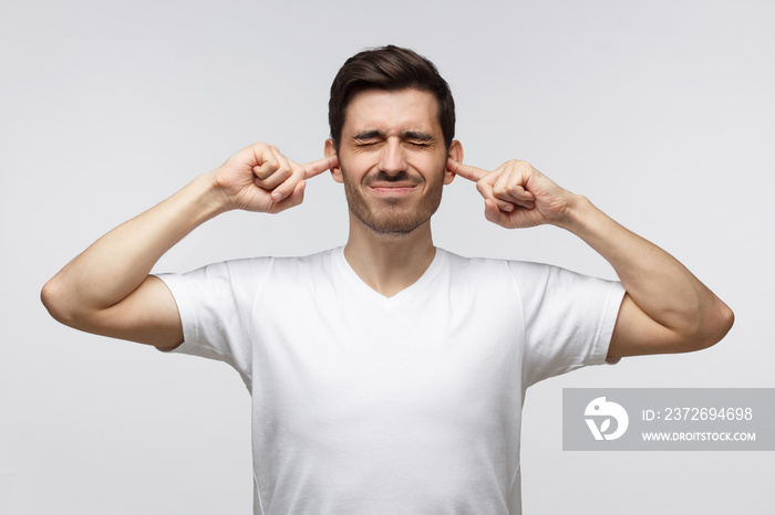 European male shutting his ears troubled by party of neighbors, isolated on background