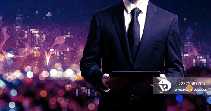 Businessman holding a tablet computer on night city background