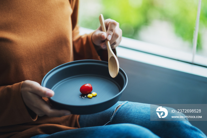 Closeup image of a woman holding a plate of small amount of food for diet concept