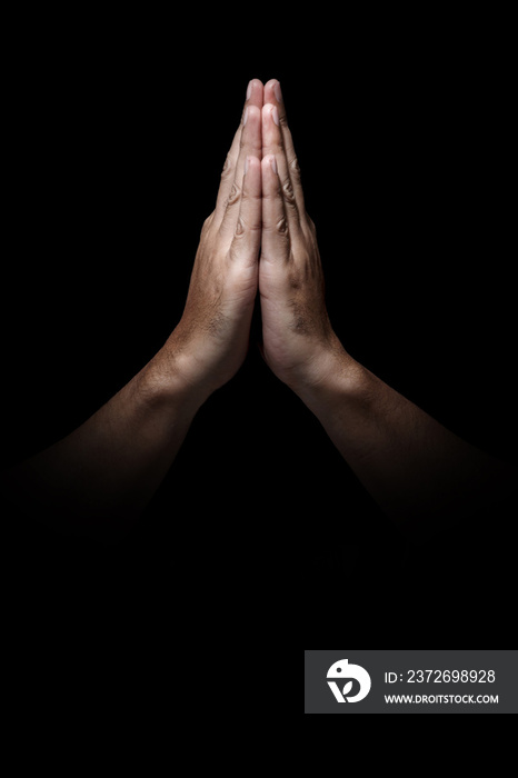 Man hands in praying position low key image. High Contrast isolated  on Black Background. Copy Space