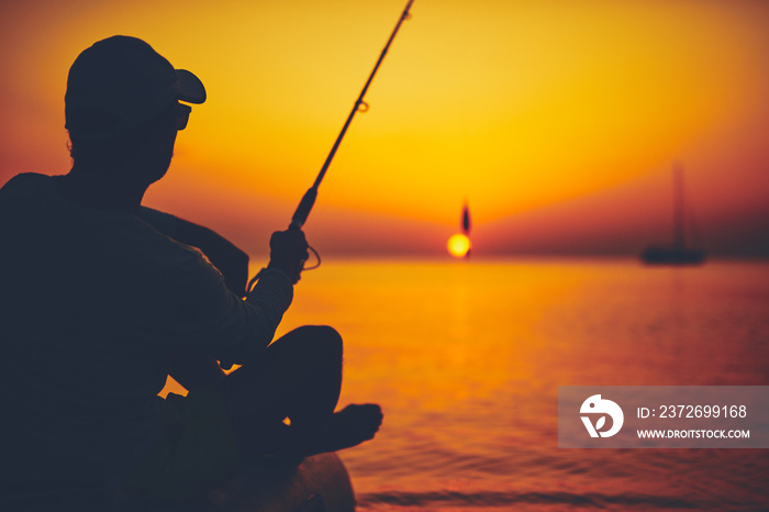 Silhouette of a fisherman fishing in sunset time on the open sea.