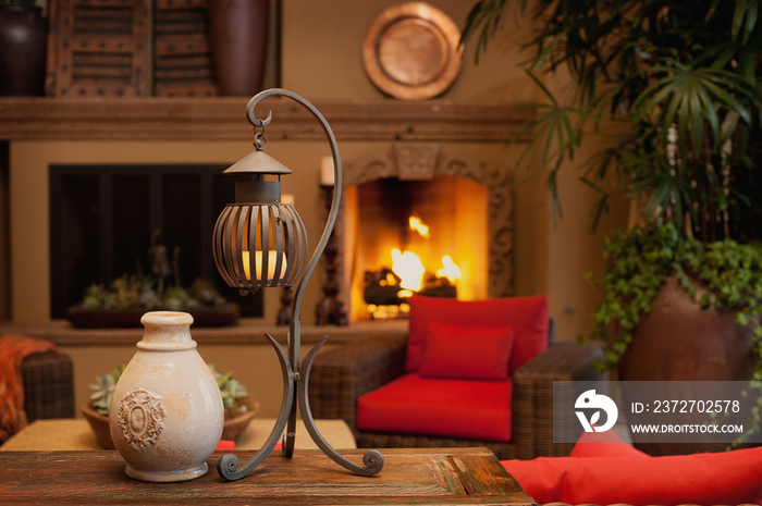 Pot with candle lantern on table against lit fireplace in living room at home; Scottsdale; USA