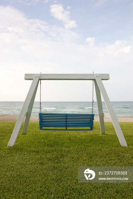 A wooden beach swing with a green painted seat