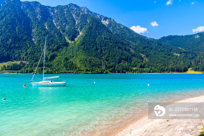 Boat on water of beautiful Achensee lake beach on sunny summer day, Tirol, Austria