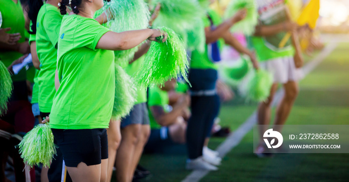 Asian cheerleader team on green artificial turf.