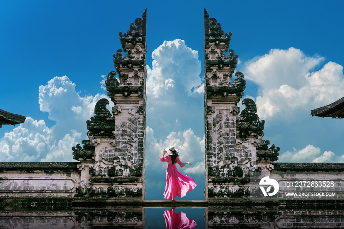 Young woman standing in temple gates at Lempuyang Luhur temple in Bali, Indonesia. Vintage tone.