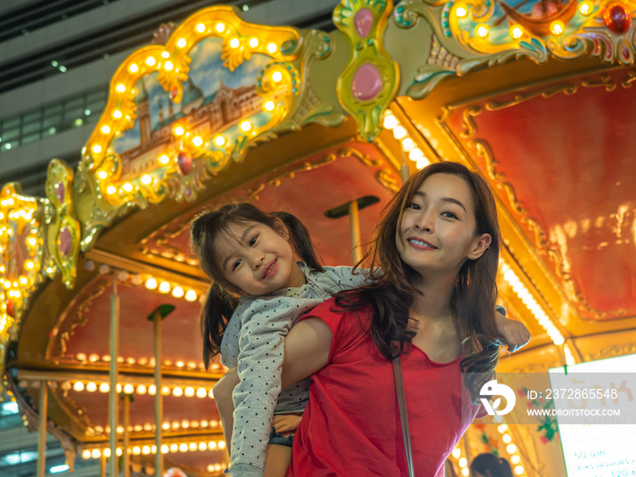 快乐亚洲母女在嘉年华游乐园玩得很开心，有法里斯转轮和旋转木马ba