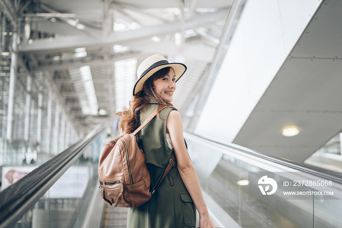 Smile Asian woman traveler walking dragging a suitcase in an airport