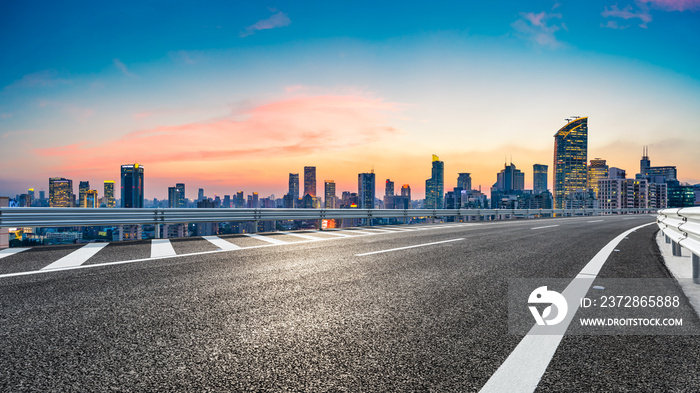 Empty asphalt road and city skyline with buildings at sunset in Shanghai.