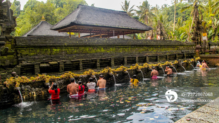 人们正在Tirta Empul寺庙进行净化沐浴仪式，这是一座印度教巴厘岛水神庙。