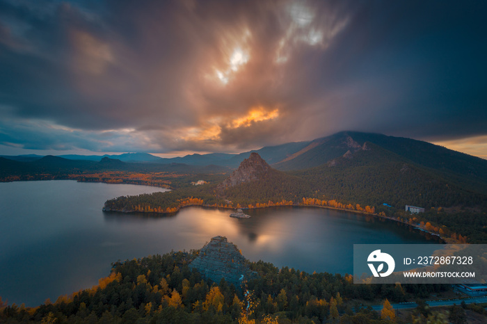 Dramatic autumn evening cloudscape at sunset. The bright colors of autumn around mountain lake. Kaza