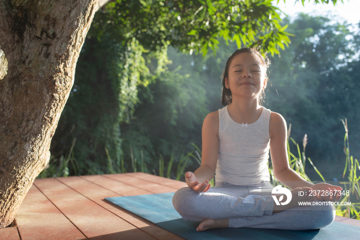 Child doing exercise healthy in sportive top and leggings practicing yoga at in nature. sitting in l