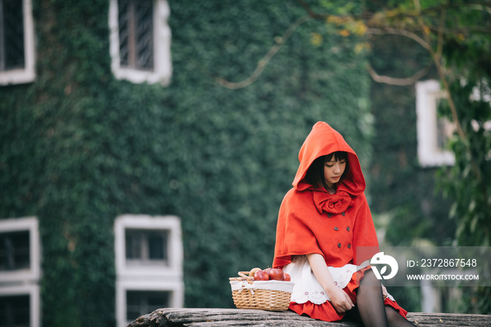 一位身穿小红帽服装、篮子里放着苹果和面包的年轻女子的肖像