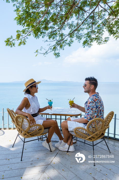一对夫妇在一家餐厅吃午饭，俯瞰泰国芭堤雅的海洋，男人和女人哈