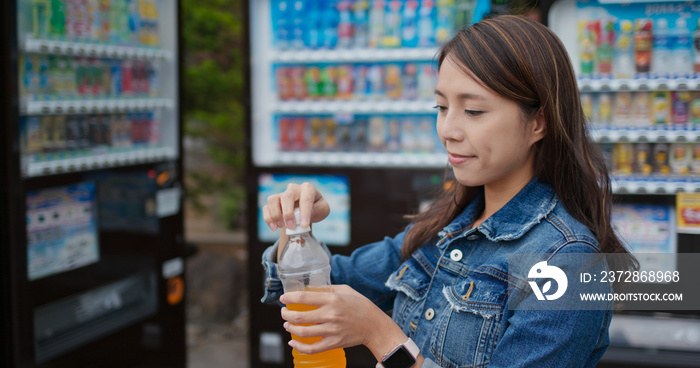 Woman drink a bottle of juice at vending machine