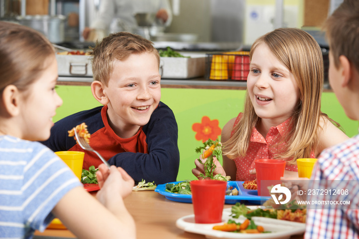 一群学生坐在学校食堂的桌子上吃午餐