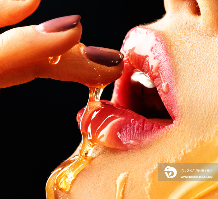 Honey dripping on sexy girl lips. Beauty model woman eating honey. Closeup image