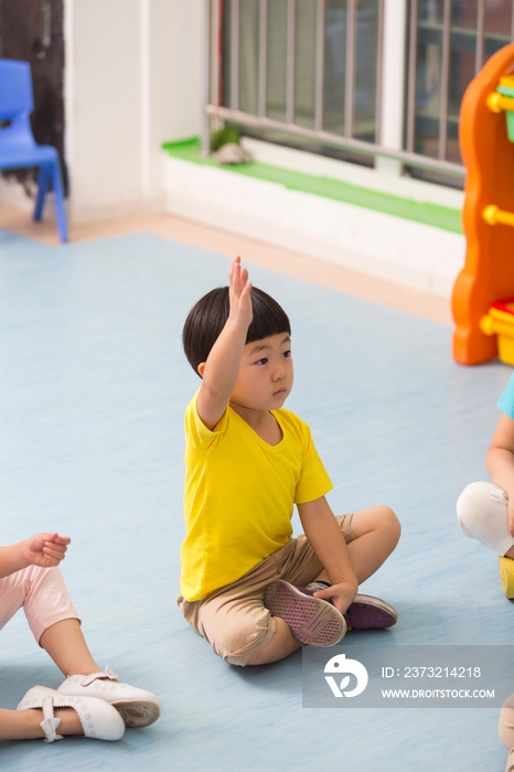 幼儿园儿童举起手回答提问