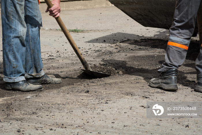 Workers cleaned the old asphalt with shovels