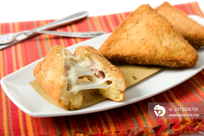 a typical dish of Roman cuisine in Italy called mozzarella in carrozza, bread in fried breadcrumbs and with stringy mozzarella on the bottom of a red placemat