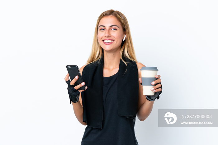 Blonde Uruguayan sport girl isolated on white background holding coffee to take away and a mobile