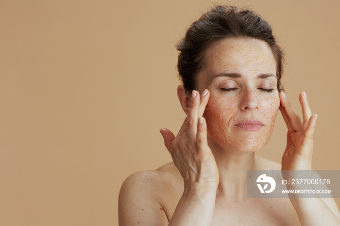 young woman with face scrub isolated on beige