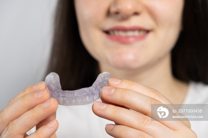 A woman holds dental mouthguard, splint for the treatment of dysfunction of the temporomandibular joints, bruxism, malocclusion, to relax the muscles of the jaw.