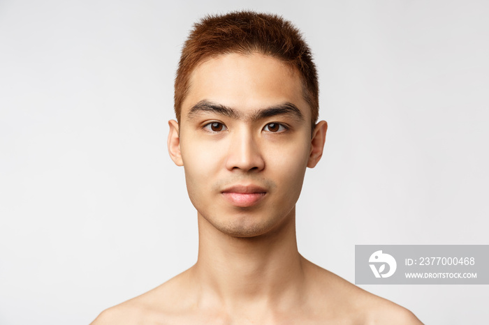 Beauty, skincare and men health concept. Headshot of handsome young asian man with no blemishes, perfect skin condition without acne, smiling enthusiastic, standing white background