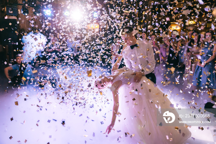 Lots of confetti fall over wedding couple dancing on the porch.