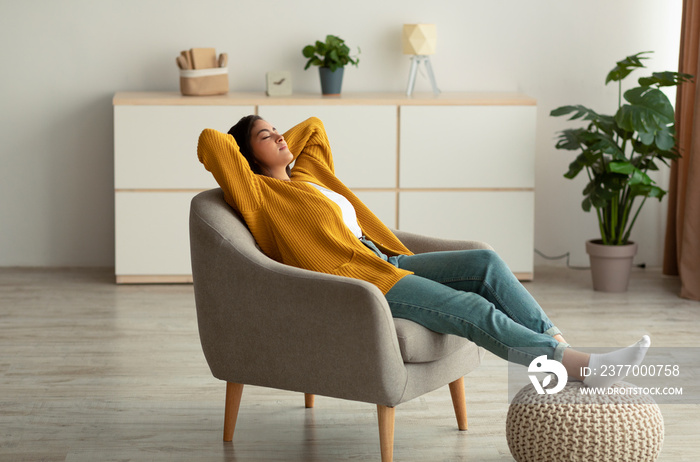 Relaxed arab woman resting in comfortable armchair, lady sitting in chair with hands behind head and closed eyes