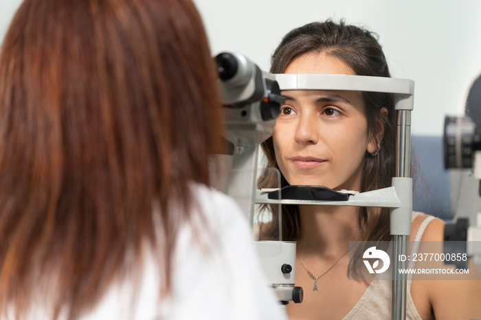 Optometrist woman examining the eyesight of another woman with a slit lamp