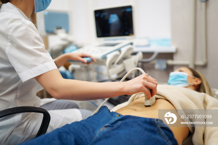 Doctor makes the patient women abdominal ultrasound. Ultrasound Scanner in the hands of a doctor. Diagnostics. Sonography. Pregnancy.